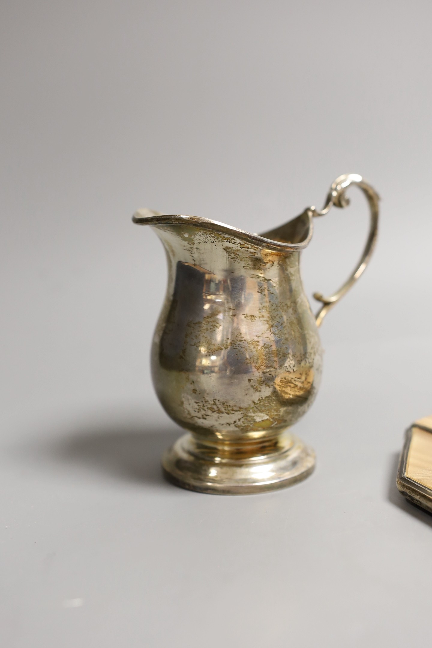 A George V silver two handled pedestal cup, Charles Edwards, London, 1923, height 13.2cm, an Art Deco silver and enamelled hand mirror, Birmingham, 1933, a silver oval trinket box, a silver cream jug and a pair of silver